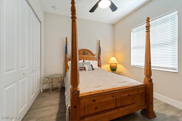 bedroom with a closet, wood finished floors, baseboards, and a ceiling fan