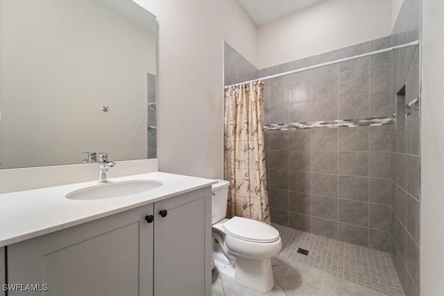 bathroom featuring tile patterned floors, toilet, tiled shower, and vanity