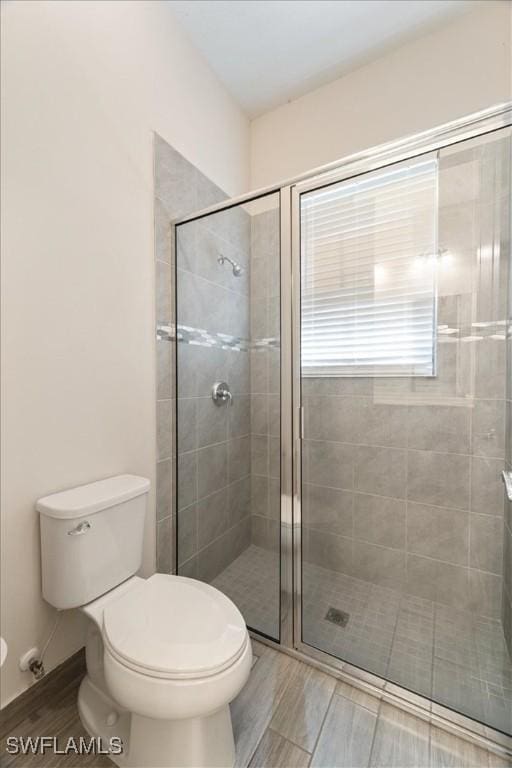 full bathroom featuring a shower stall, toilet, and wood finished floors