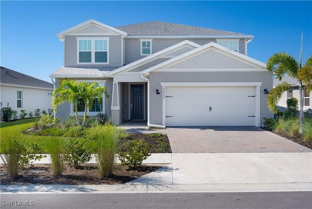 view of front of home featuring a shingled roof, a garage, and decorative driveway