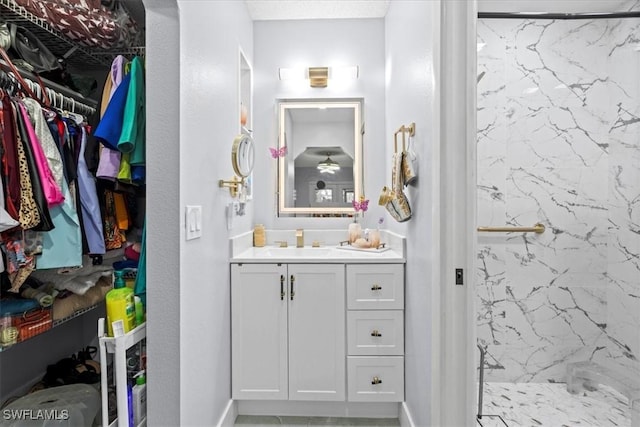25068 Harborview Rd Unit 1B, Punta Gorda, FL 33980 - bathroom with baseboards, a spacious closet, vanity, and a marble finish shower