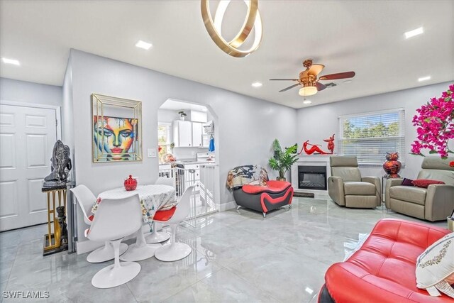 25068 Harborview Rd Unit 1B, Punta Gorda, FL 33980 - living room with a glass covered fireplace, ceiling fan, arched walkways, marble finish floor, and baseboards