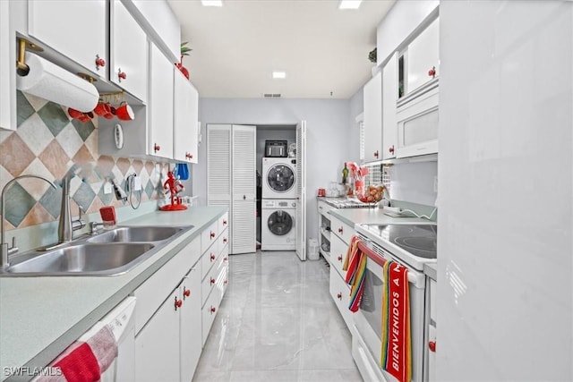 25068 Harborview Rd Unit 1B, Punta Gorda, FL 33980 - kitchen with white cabinets, a sink, white appliances, stacked washer / drying machine, and light countertops