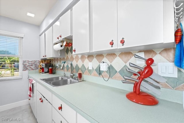 25068 Harborview Rd Unit 1B, Punta Gorda, FL 33980 - kitchen featuring a sink, decorative backsplash, light countertops, baseboards, and white cabinetry