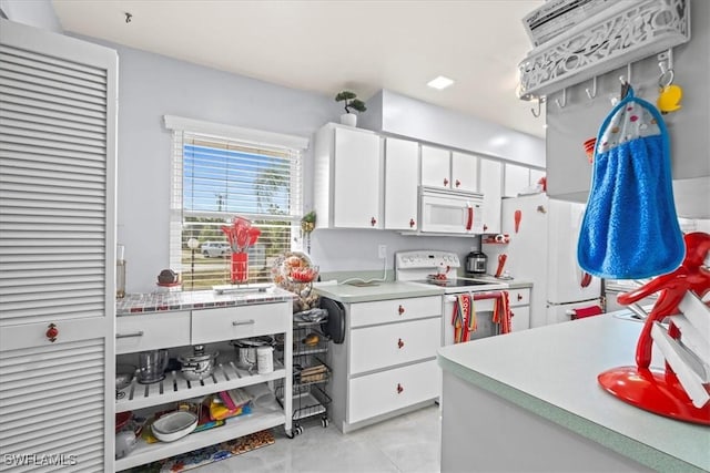 25068 Harborview Rd Unit 1B, Punta Gorda, FL 33980 - kitchen featuring light tile patterned floors, white cabinetry, white appliances, and light countertops