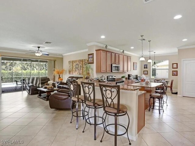 8143 Monticello Ct, Naples, FL 34104 - kitchen with stone counters, ornamental molding, a breakfast bar, appliances with stainless steel finishes, and light tile patterned flooring