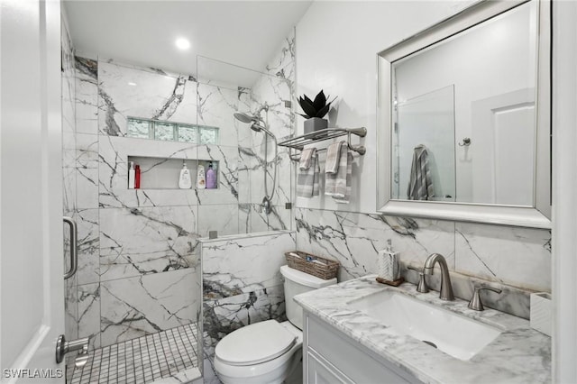 bathroom with a marble finish shower, vanity, toilet, and tile walls