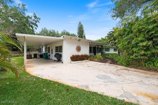 1147 Shady Rest Ln, Naples, FL 34103 - rear view of house with stucco siding, a carport, and concrete driveway
