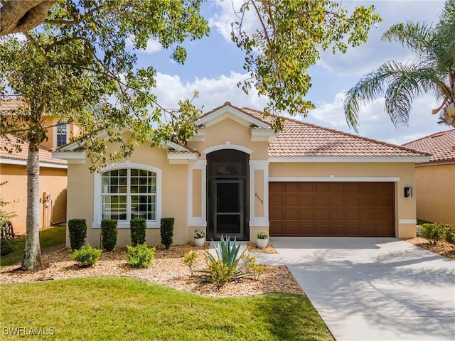 mediterranean / spanish house with stucco siding, a tiled roof, a front yard, concrete driveway, and an attached garage