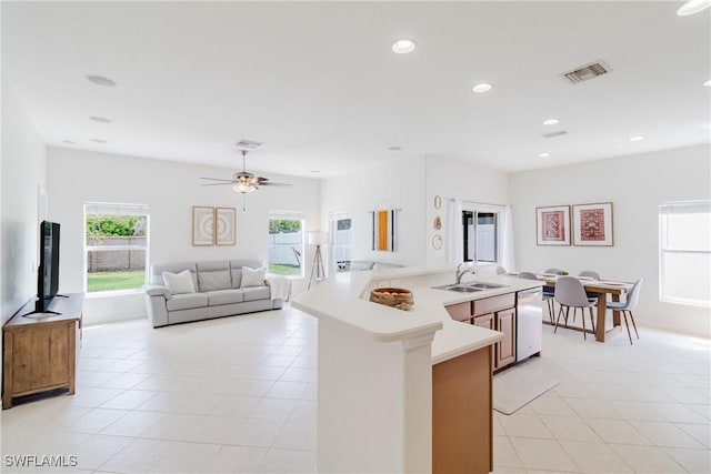 kitchen with stainless steel dishwasher, light tile patterned floors, light countertops, a sink, and visible vents