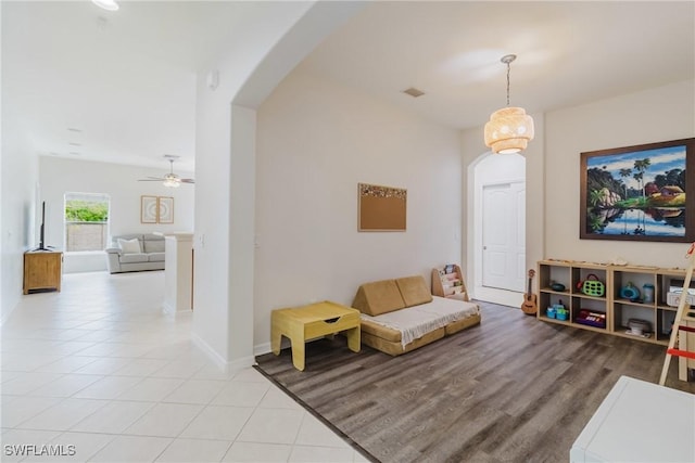 living room with light tile patterned flooring, visible vents, baseboards, and arched walkways