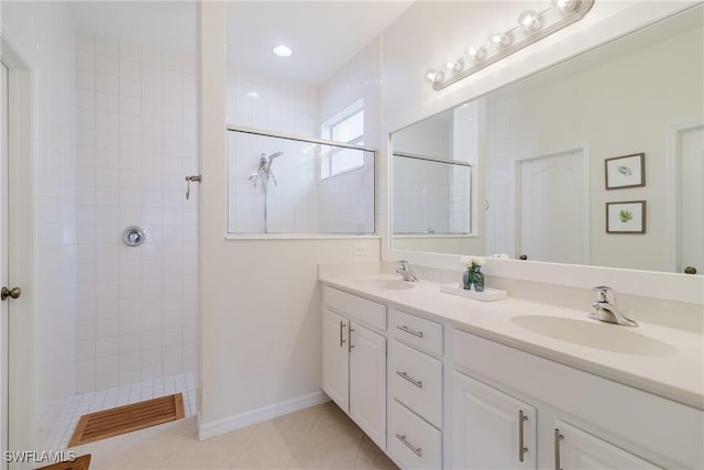 full bathroom featuring tile patterned floors, a tile shower, double vanity, and a sink