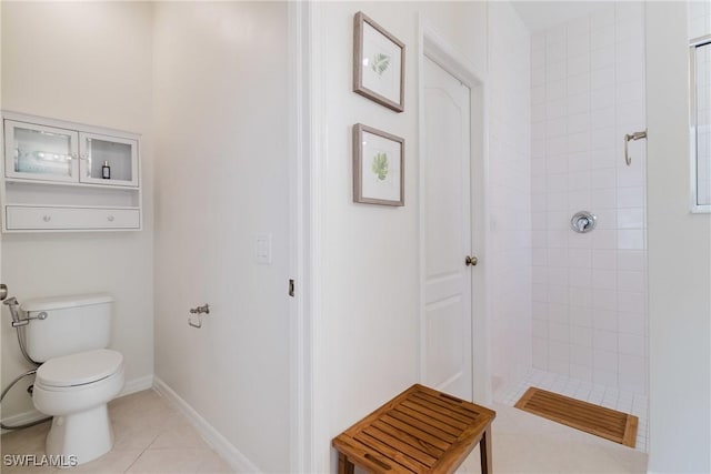 full bathroom featuring tile patterned floors, toilet, baseboards, and tiled shower
