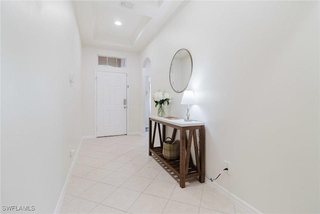 corridor featuring light tile patterned flooring, arched walkways, visible vents, and baseboards