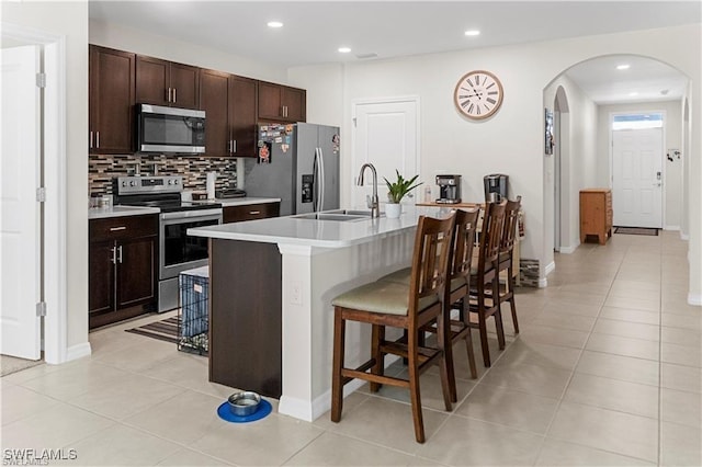 8880 Cascade Price Cir, North Fort Myers, FL 33917 - kitchen with stainless steel appliances, arched walkways, a kitchen breakfast bar, decorative backsplash, and recessed lighting