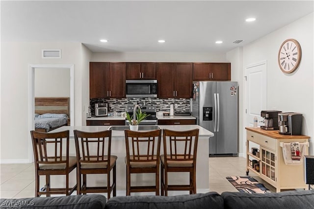 8880 Cascade Price Cir, North Fort Myers, FL 33917 - kitchen featuring stainless steel appliances, light tile patterned flooring, light countertops, dark brown cabinets, and a breakfast bar area