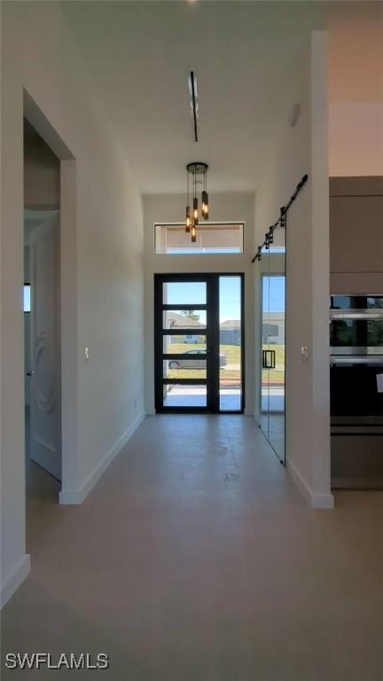308 SW 13th Ct, Cape Coral, FL 33991 - corridor with finished concrete floors, baseboards, and an inviting chandelier