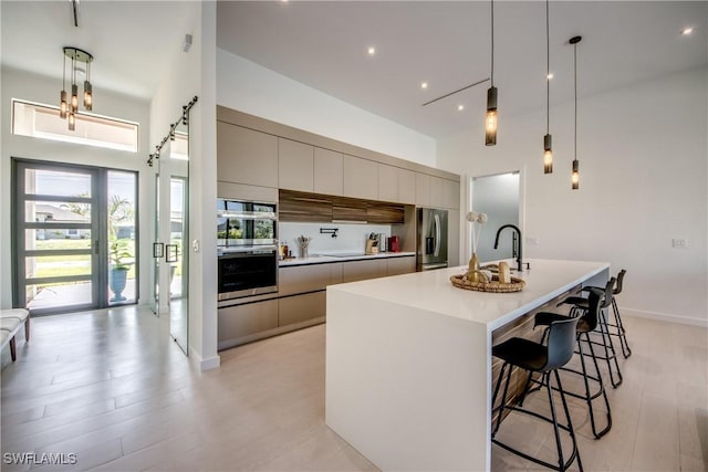 308 SW 13th Ct, Cape Coral, FL 33991 - kitchen featuring modern cabinets, stainless steel appliances, a towering ceiling, a breakfast bar area, and light countertops