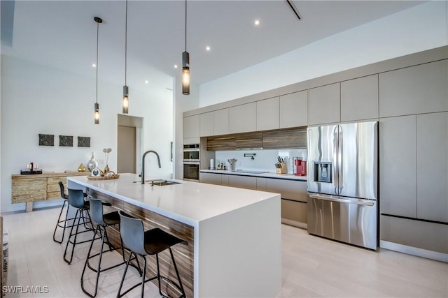 308 SW 13th Ct, Cape Coral, FL 33991 - kitchen featuring stainless steel appliances, modern cabinets, light wood finished floors, a towering ceiling, and a breakfast bar area
