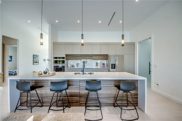 308 SW 13th Ct, Cape Coral, FL 33991 - kitchen with stainless steel appliances, modern cabinets, a kitchen bar, light countertops, and hanging light fixtures