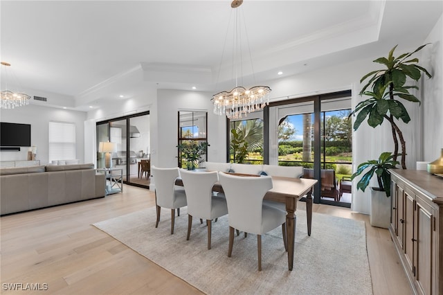 dining room featuring an inviting chandelier, light wood finished floors, visible vents, and a raised ceiling