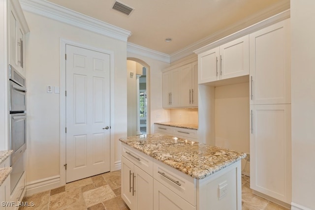 10326 Wishing Stone Ct, Bonita Springs, FL 34135 - kitchen featuring visible vents, white cabinets, arched walkways, ornamental molding, and light stone counters