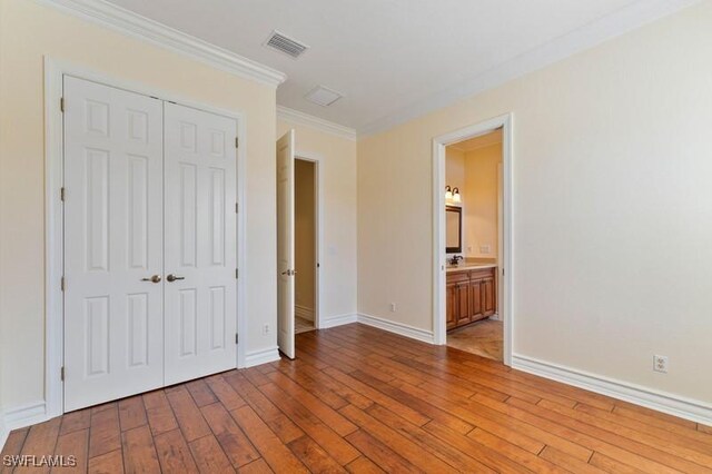 10326 Wishing Stone Ct, Bonita Springs, FL 34135 - unfurnished bedroom with visible vents, baseboards, a closet, hardwood / wood-style flooring, and crown molding