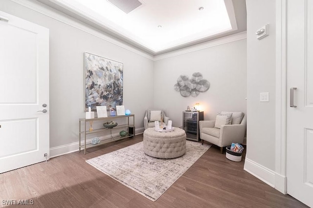 sitting room with wood finished floors, baseboards, and ornamental molding