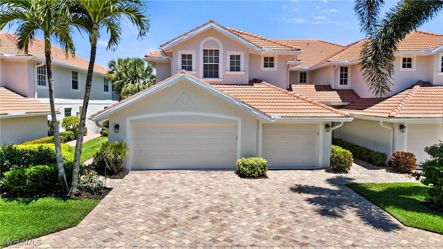view of front of property with stucco siding, decorative driveway, and a tiled roof
