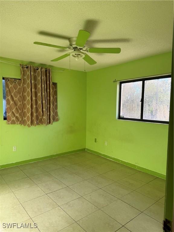 338 Melody Ct, Fort Myers, FL 33916 - empty room featuring light tile patterned flooring, a ceiling fan, a textured ceiling, and baseboards