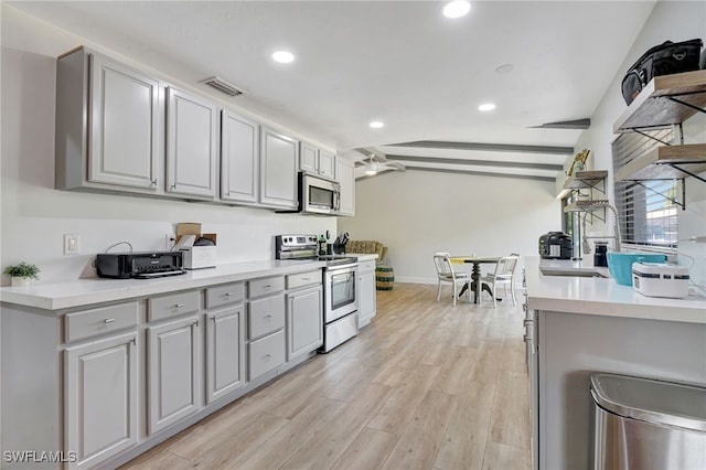 2226 SE 19th Pl, Cape Coral, FL 33990 - kitchen featuring open shelves, light countertops, vaulted ceiling, light wood-style flooring, and appliances with stainless steel finishes