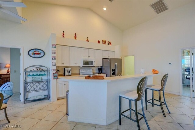 330 SW 33rd Ave, Cape Coral, FL 33991 - kitchen with light tile patterned floors, visible vents, white appliances, and high vaulted ceiling
