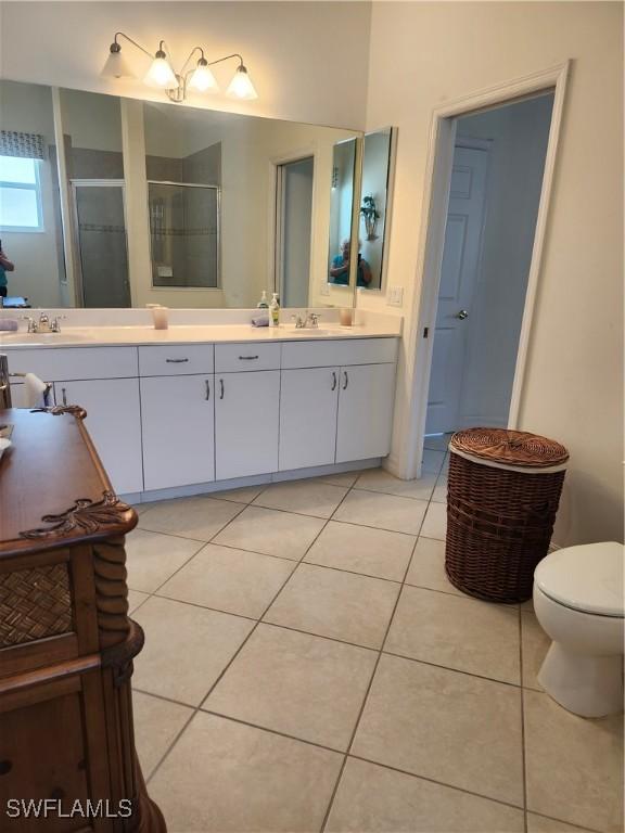 330 SW 33rd Ave, Cape Coral, FL 33991 - bathroom featuring a sink, a shower stall, toilet, double vanity, and tile patterned flooring