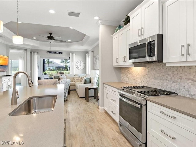 2138 Marquesa Cir, Naples, FL 34112 - kitchen with stainless steel appliances, a tray ceiling, a sink, crown molding, and a ceiling fan