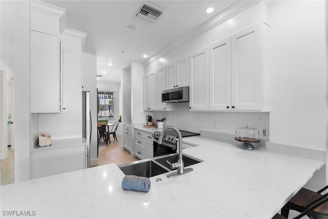 7915 Mahogany Run Ln Unit 1126, Naples, FL 34113 - kitchen with stainless steel appliances, white cabinets, recessed lighting, light stone counters, and a breakfast bar