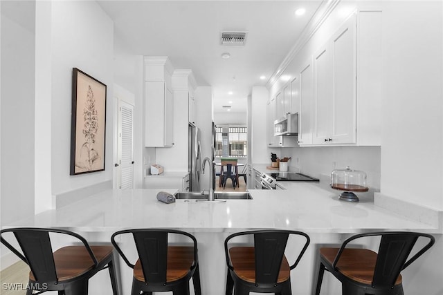 7915 Mahogany Run Ln Unit 1126, Naples, FL 34113 - kitchen with stainless steel appliances, a peninsula, white cabinets, light countertops, and recessed lighting