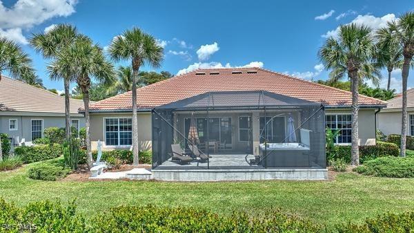 back of property with a tiled roof, glass enclosure, stucco siding, and a patio area
