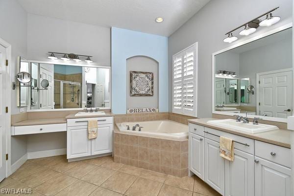full bath featuring a sink, a bath, tile patterned flooring, and a stall shower