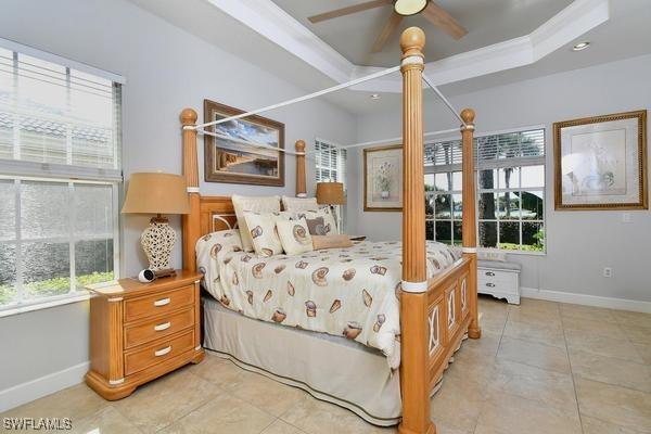 bedroom featuring light tile patterned floors, multiple windows, baseboards, and a raised ceiling