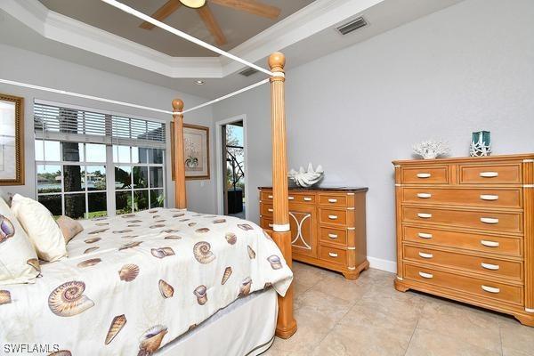bedroom with light tile patterned floors, ceiling fan, ornamental molding, visible vents, and a raised ceiling