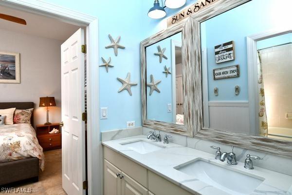 bathroom with double vanity, a sink, and connected bathroom