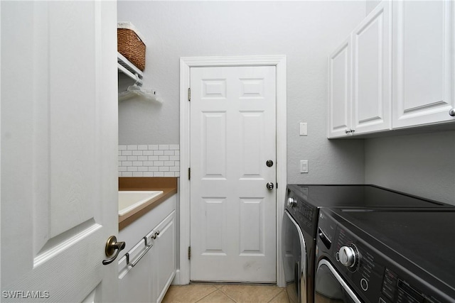 laundry room featuring light tile patterned floors, washing machine and dryer, a sink, and cabinet space