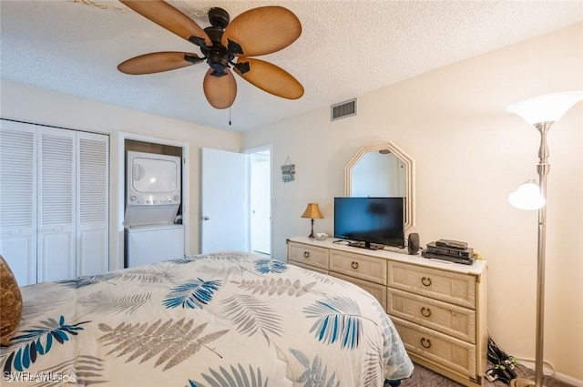 bedroom with stacked washing machine and dryer, ceiling fan, a closet, and a textured ceiling
