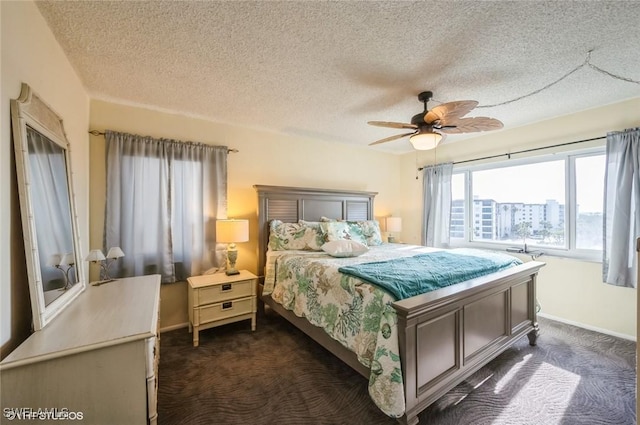 bedroom with dark colored carpet, a textured ceiling, baseboards, and a ceiling fan