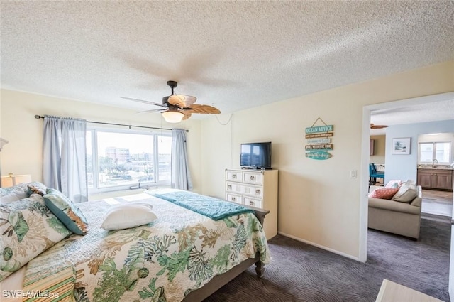 carpeted bedroom with a sink, a textured ceiling, ceiling fan, and baseboards
