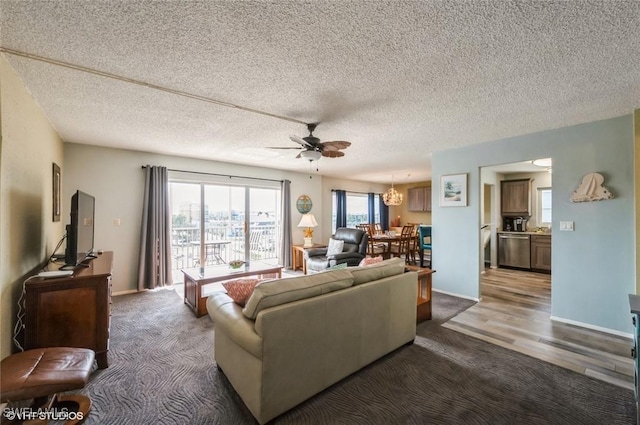 living area with carpet, a ceiling fan, a chandelier, baseboards, and a textured ceiling