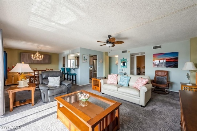 living room featuring light colored carpet, a chandelier, a ceiling fan, and a textured ceiling