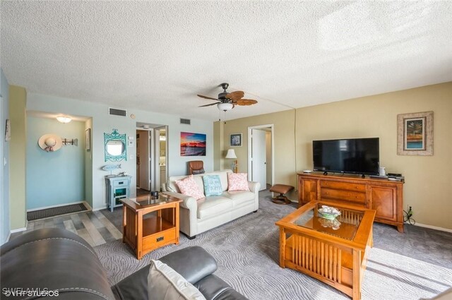 carpeted living area featuring a textured ceiling, ceiling fan, and baseboards