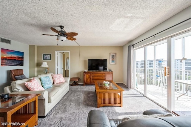 carpeted living area with ceiling fan and a textured ceiling