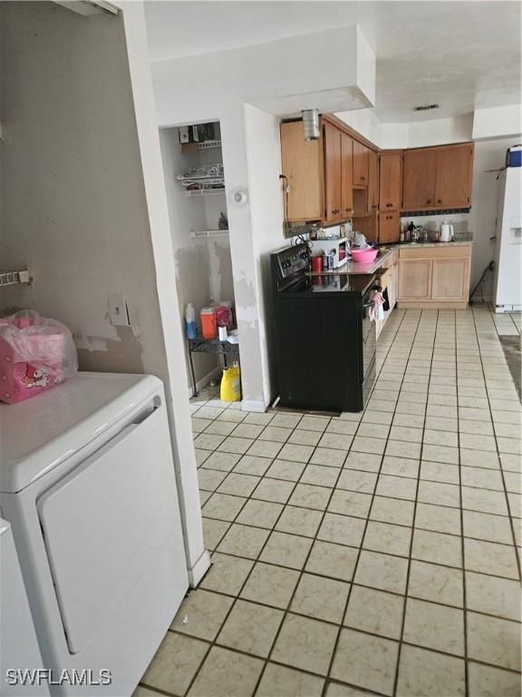 2631 Becca Ave, Naples, FL 34112 - kitchen featuring light tile patterned floors, white fridge with ice dispenser, black electric range, washer / dryer, and brown cabinets